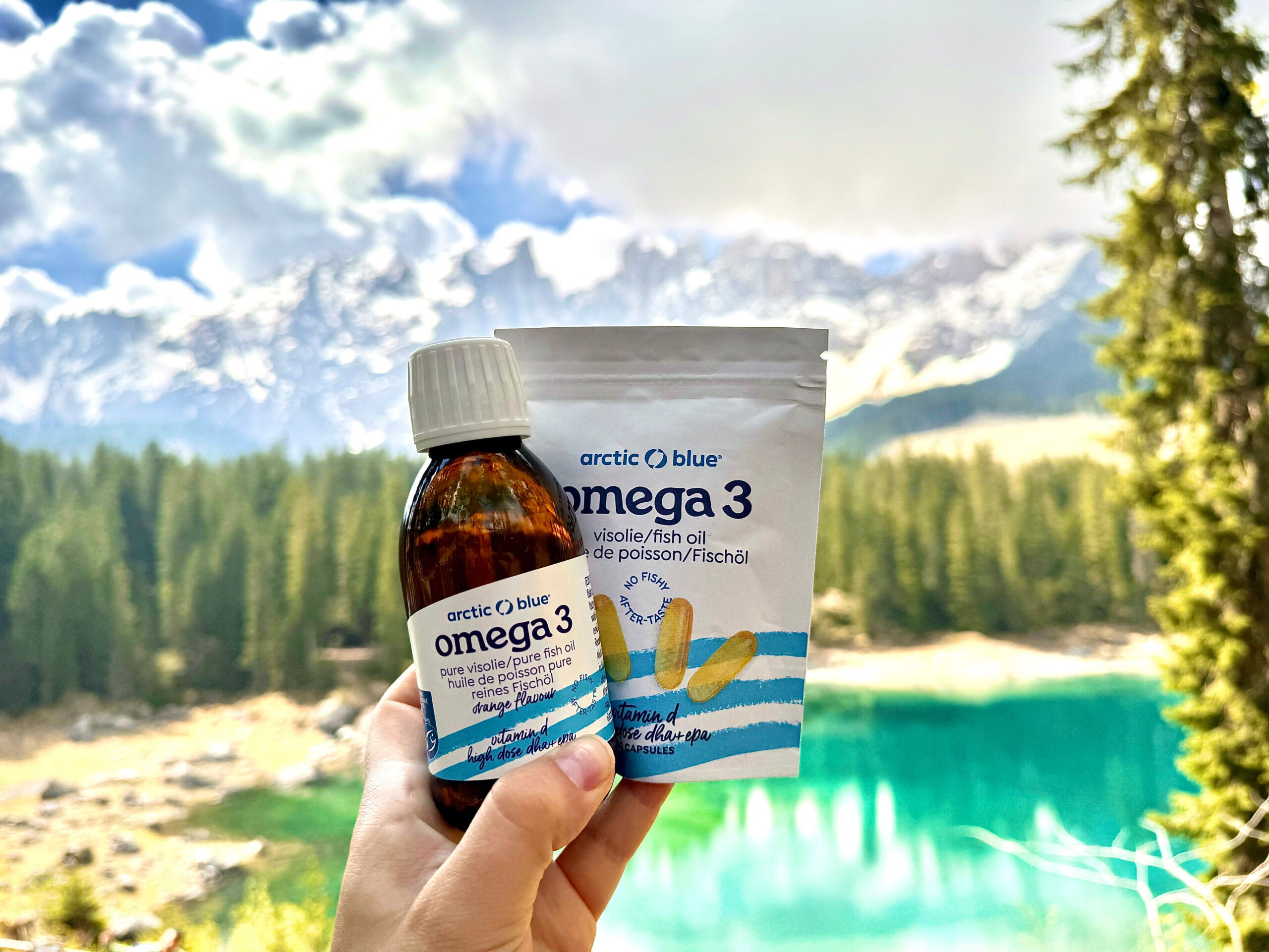arctic blue liquid fish oil and capsules with a lake and a forest in the background